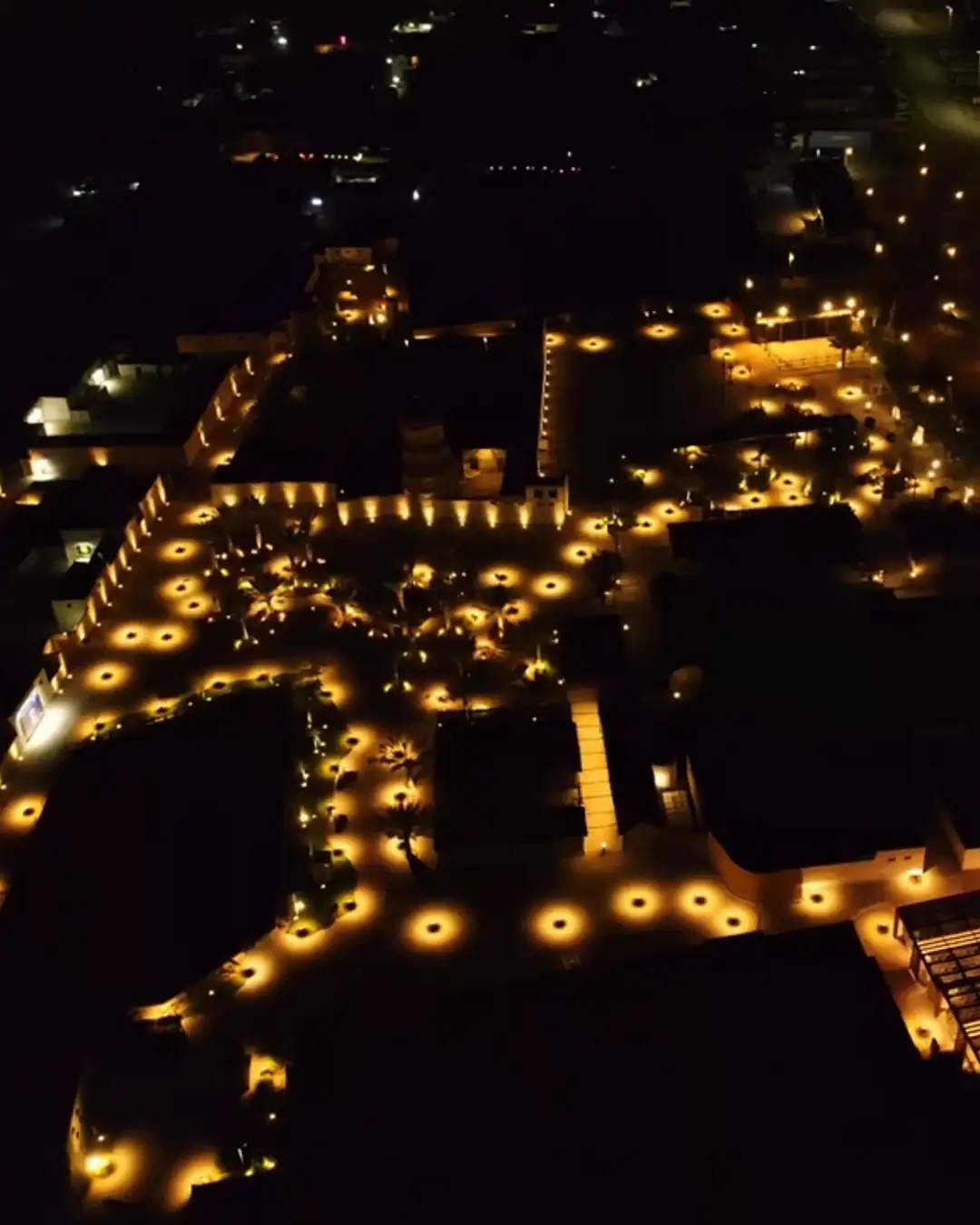 Il villaggio storico di Al Jazira Al Hamra di notte, visto dall'alto: i percorsi sono disegnati dalle file dei paletti accesi
