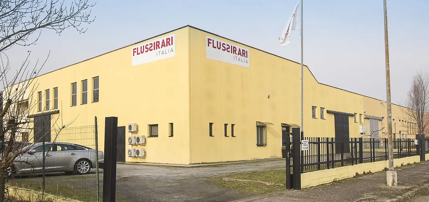 Lo stabilimento Flussirari a Novi Ligure: un capannone giallo con l'insegna FLUSSIRARI ITALIA